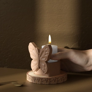 Close-up of butterfly embossed resin candle holder on a rustic natural wood tray