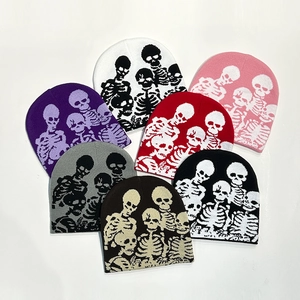Detailed flat lay of knitted skull beanies in seven various colors on a white background