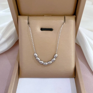 Macro view of silver beaded titanium steel necklace displayed in a beige jewelry box