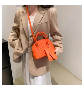 Détail d'un sac à main matelassé orange avec pochette assortie et bandoulière amovible