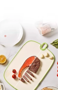 Dual-sided antibacterial cutting board with green non-slip edges and hanging hole detail
