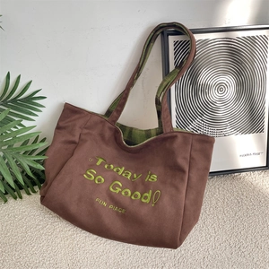 Detail view of brown suede tote bag featuring green embroidery and checkered lining