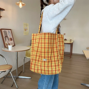 Detailed view of a yellow checkered canvas tote bag in a cozy minimalist cafe setting