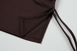 Detailed close-up of brown ribbed knit fabric with side slit and adjustable drawstring