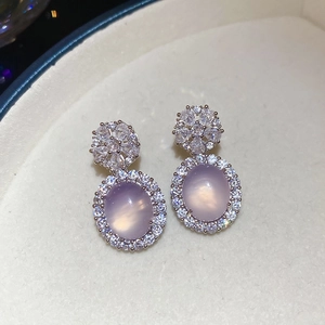 Gros plan de boucles d'oreilles en argent avec calcédoine violette et détails floraux