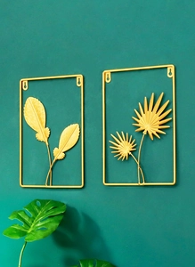 Close-up of golden iron wall decor featuring feather and palm leaf designs on blue wall