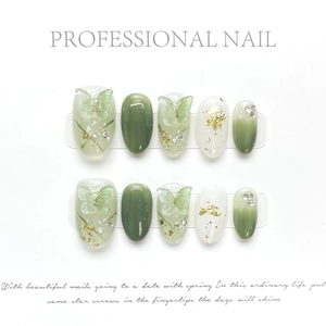 Detail of handmade press-on nails with green butterfly and sparkling rhinestone accents