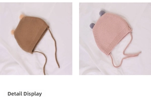 Detail view of baby knitted earflap hats with pom-poms in warm brown and soft pink