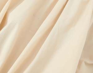 Detailed macro view of beige poplin midi dress fabric showing cotton weave and soft texture