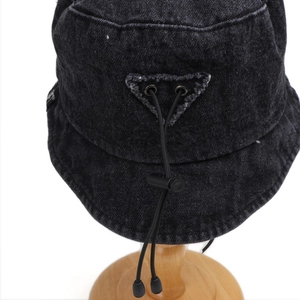 Detailed view of black denim bucket hat with adjustable drawstring and metal hardware