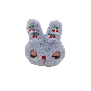 Cute plush rabbit head accessory with cherry embroidery and closed eyes on white background
