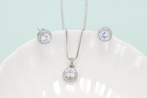 Classic silver halo jewelry set with round clear stones in a seashell ceramic dish