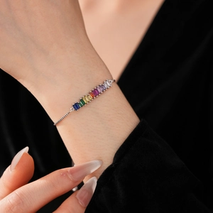 Detail of adjustable silver bracelet featuring rainbow-colored rectangular zircons on wrist