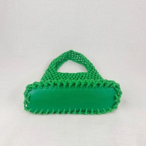 Detail of green woven beach bag with handmade net structure and leather reinforced base