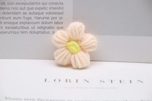 Macro shot of handmade milk cotton crochet flower in soft pink with yellow center