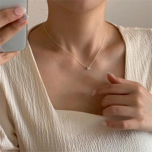 Close-up of minimalist silver 4-prong square zircon necklace on a model's collarbone
