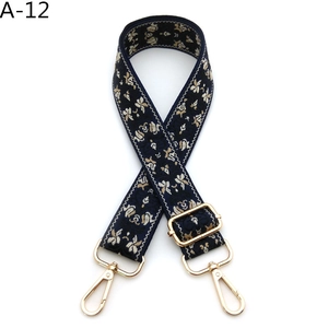 Detail of navy blue embroidered floral bag strap with adjustable gold-tone metal hardware