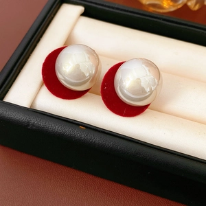 Close-up of pearl earrings with red velvet round base in a premium jewelry box display