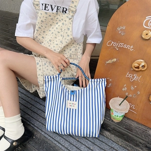 Detailed top view of striped canvas tote bag with round blue handles and woven logo label