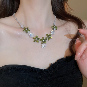 Gros plan du collier fleur en zircone porté par un mannequin avec cristaux verts