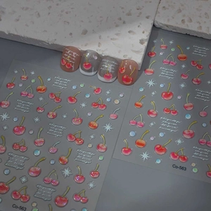 Detail of cherry nail stickers with glitter stars and floral text on display tips