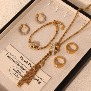 Elegant gold rhinestone jewelry set with tassel necklace and bracelet in a display tray
