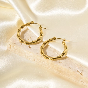Boucles d'oreilles créoles bambou en acier plaqué or 18K sur fond de soie élégant