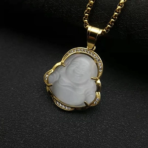 Macro shot of gold-plated Buddha pendant with white cat's eye stone and diamond accents
