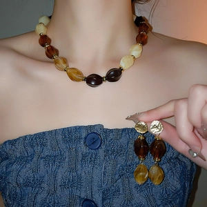 Close-up of amber acrylic necklace and earrings set worn by model in retro style