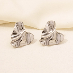 Macro shot of silver heart-shaped earrings with unique irregular pleated metal texture
