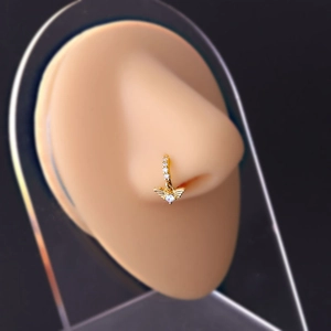 Detailed view of a gold nose ring with a sparkling angel wing pendant on a model