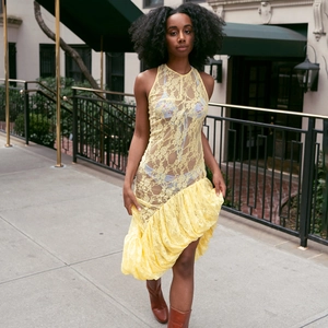 Détail de robe jaune en dentelle sans manches avec tissu transparent et ourlet volanté