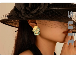 Detail of vintage 18k gold daisy earrings in green enamel on model with black lace hat