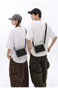 Detail of minimalist black box shoulder bag with CON KNOWS text shown on models
