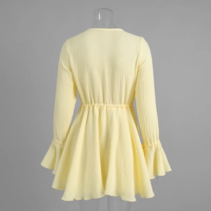 Rear view of yellow mini dress showing elastic waist, flared cuffs and crinkle texture