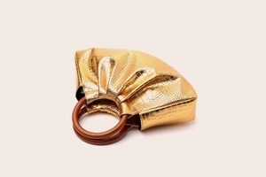 Macro shot of metallic golden crocodile pattern handbag with a round brown handle