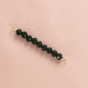 Detailed view of eight dark green faceted crystal beads with golden metal ring connectors