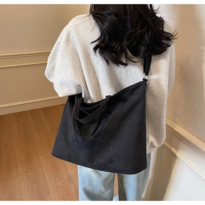 Large black canvas tote bag shown worn on shoulder for daily casual commuting style