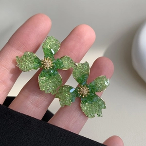 Close-up of green crystal flower earrings with gold stamens and ice-cracked texture