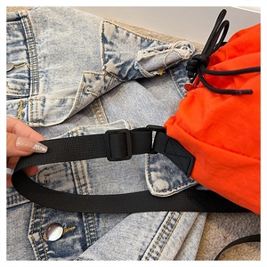 Detail of orange nylon bucket bag with adjustable black wide strap and plastic buckle
