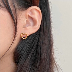 Elegant 925 sterling silver hollow heart stud earrings in gold worn by a female model