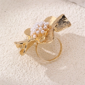 Detailed view of a gold flower ring with hammered petals and a white pearl center