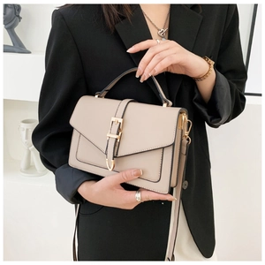 Detail of minimalist beige handbag with gold metal buckle and detachable shoulder strap