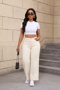 Détail d'un jean large à taille haute crème avec un haut court blanc pour femmes