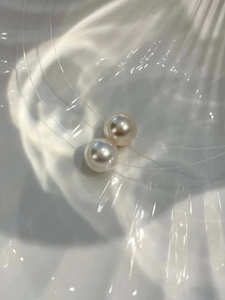 Close-up of white and pink pearls with metallic luster in a white shell dish