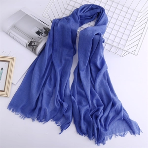 Blue cotton linen scarf with fringe edges displayed on a decorative grid rack