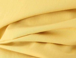 Close-up of bright yellow woven fabric texture with natural soft drape and fine fiber detail