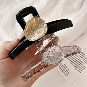 Detail of elegant large hair claw clips with irregular metal plates and numbered engraving