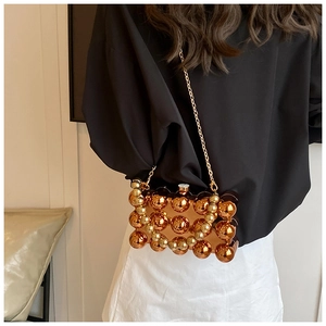 Close-up of golden acrylic spherical crossbody bag with elegant metal chain strap