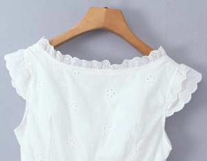 Détail d'un haut blanc sans manches avec broderie ajourée et finitions en dentelle